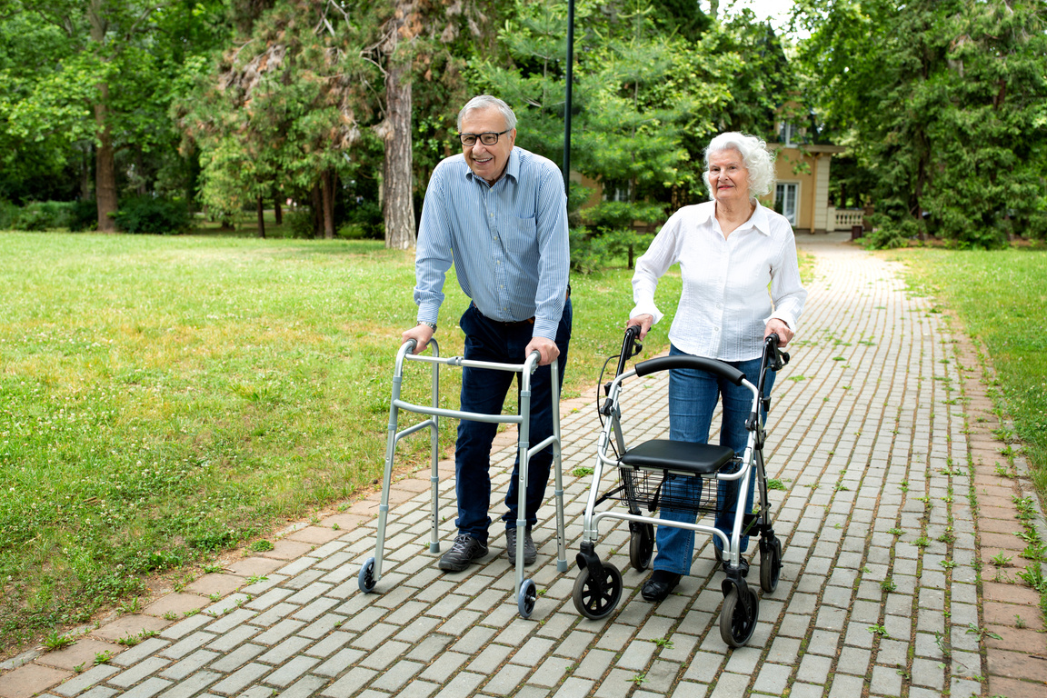 Senior citizens walking through the park with walking aid
